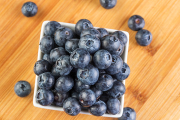 Fresh blueberry in white plate photographed against wooden background