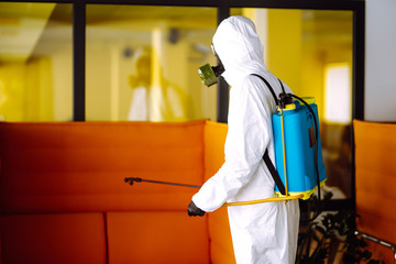 Fototapeta na wymiar Disinfecting of office to prevent COVID-19, Man in protective hazmat suit with with spray chemicals to preventing the spread of coronavirus, pandemic in quarantine city. Cleaning concept.