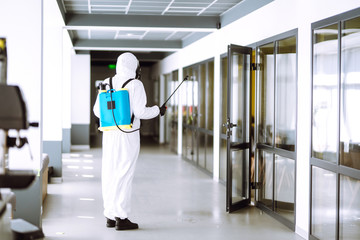 Disinfecting of office to prevent COVID-19, Man in protective hazmat suit with  with spray chemicals to preventing the spread of coronavirus, pandemic in quarantine city. Cleaning concept.