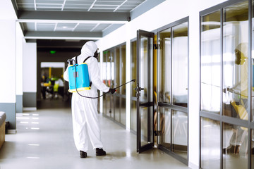 Disinfecting of office to prevent COVID-19, Man in protective hazmat suit with  with spray chemicals to preventing the spread of coronavirus, pandemic in quarantine city. Cleaning concept.