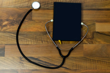 black book and stethoscope on wooden table 