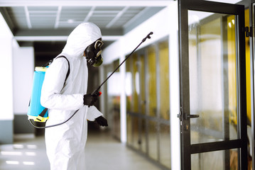 Disinfecting of office to prevent COVID-19, Man in protective hazmat suit with  with spray chemicals to preventing the spread of coronavirus, pandemic in quarantine city. Cleaning concept.