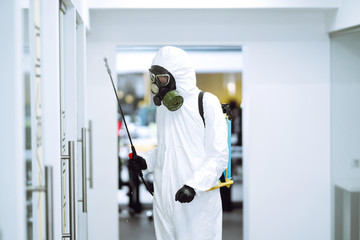 Disinfecting of office to prevent COVID-19, Man in protective hazmat suit with  with spray chemicals to preventing the spread of coronavirus, pandemic in quarantine city. Cleaning concept.