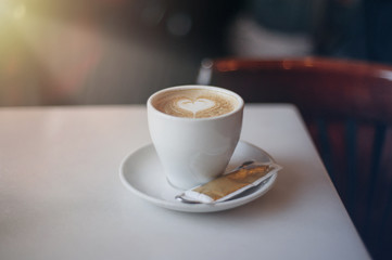 A cup of coffee on a table with a drawn heart 