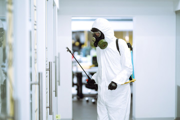 Fototapeta premium Disinfecting of office to prevent COVID-19, Man in protective hazmat suit with with spray chemicals to preventing the spread of coronavirus, pandemic in quarantine city. Cleaning concept.