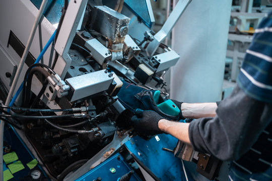 man working with automatic machinery on shoe factory
