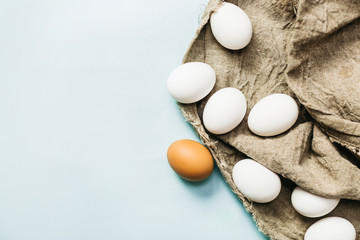 Fresh natural eggs lie on a fabric, on a blue background. Bright Easter holiday, symbol, cooking,close up