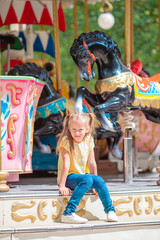 Adorable little girl near the carousel outdoors