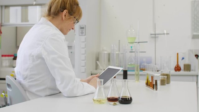 Close up of chemist working with hemp CBD oil and tablet in laboratory