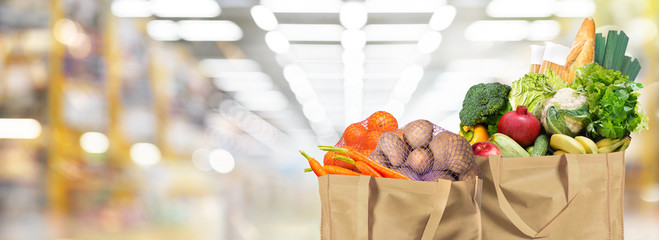 Eco friendly reusable shopping bags filled with bread, fruits and vegetables on a supermarket...