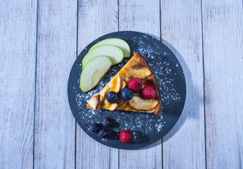 slice of apple pie on a slate plate with a white wooden surface, top view, dessert concept.