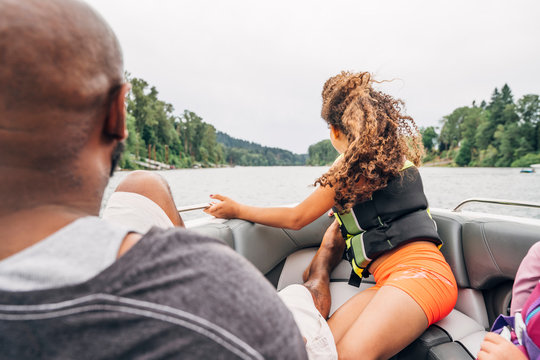 Dad and daughter on boat in lake surrounded by trees 
