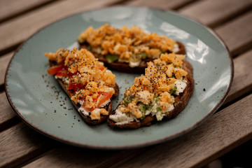 Avocado toasts with scrambled eggs, feta cheese and tomatoes