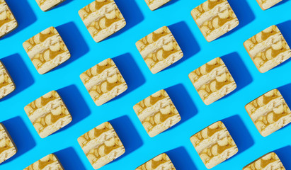 Sliced Caramel Peanut Chocolate on Blue Background with same shadows. Abstract Food Background in Flat Lay Style Top View