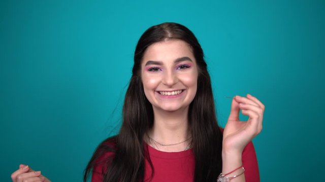 Young Happy Brunette Woman Popping A Balloon With A Needle On Blue Background