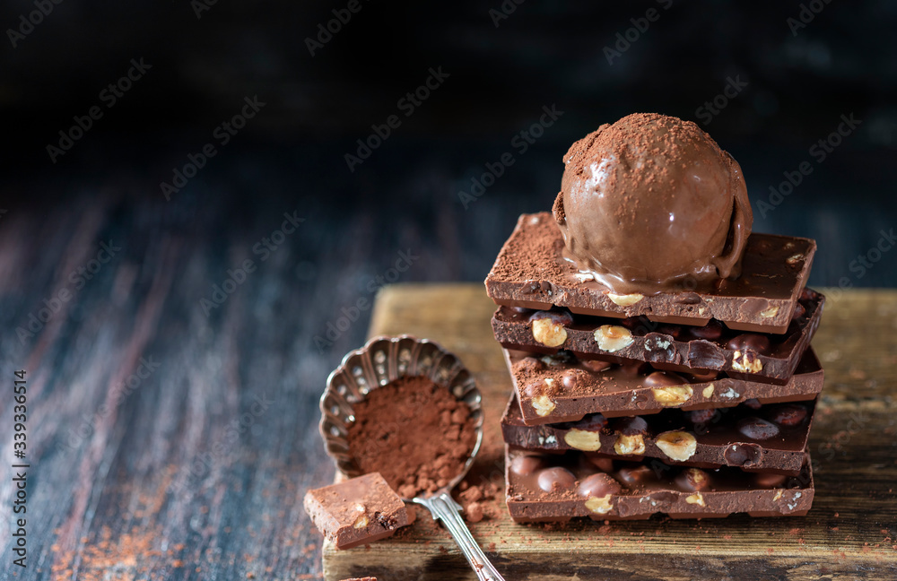 Wall mural A ball of chocolate ice cream on a chocolate bar with nuts.