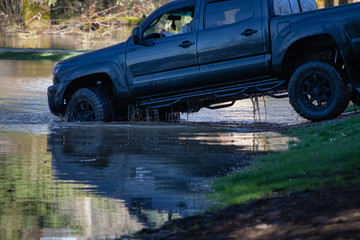 Fototapeta premium czarna ciężarówka wyjeżdżająca z zalanego parku