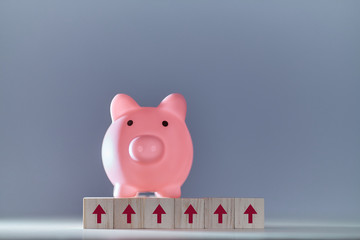Financial growth. Increase in income. Saving money. Pink piggy bank on wooden cubes with up arrows sign, copy space