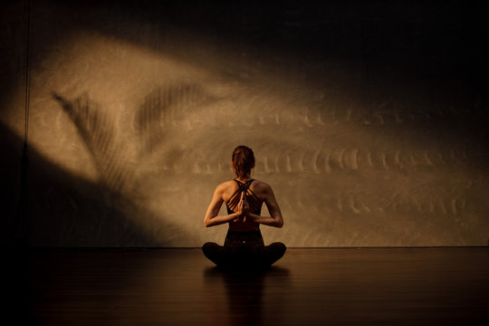 Young Asian woman practicing yoga in moody studio during golden hour