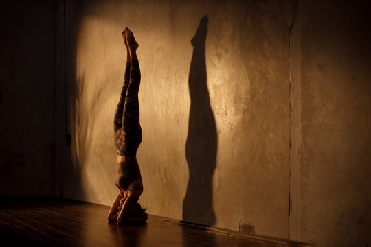 Young Asian woman practicing yoga in moody studio during golden hour
