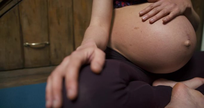 Pregnant young yoga woman feeling her belly in meditation pose