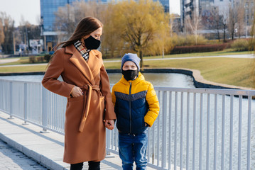 A young family walks and breathes fresh air on a Sunny day during a quarantine and pandemic. Masks on people's faces