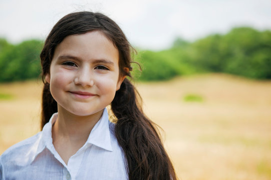 Portrait of girl out doors by field smiling at camera 