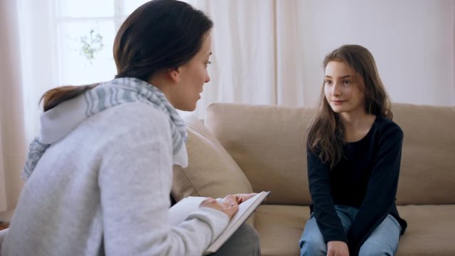Sad and depressed small girl talking to therapist indoors, mental health concept.