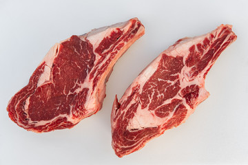 Obraz premium Choice Bone in Beef Rib Steak on a butchers counter ready for packaging.