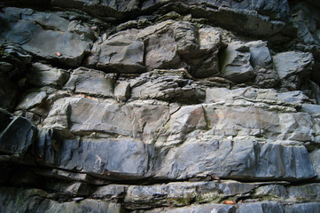 Layers of rock, dark natural stone. Mountain ridge. Wall. Geology. Natural texture, background.