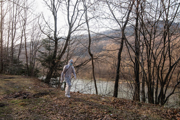 Man in protective suit run at the forest near the river.