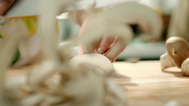 hands chopping fresh mushrooms on a cutting board then throws the mushrooms with a knife. fast.
