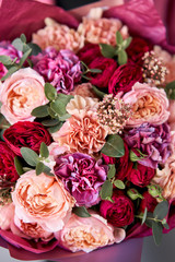 Bright berry color, Beautiful bouquet of mixed flowers in womans hands. the work of the florist at a flower shop. Delivery fresh cut flower. European floral shop.