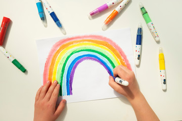 Top view of a boy drawing a rainbow