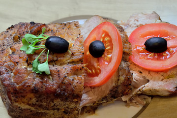 Baked meat with tomato, olives and arugula is on a plate