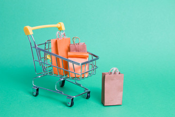 shopping trolley on a green background, small paper bags in a trolley, copy space, online shopping...