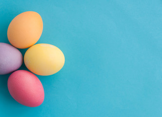 Flat lay of colourful Easter eggs in a flowe shape placed on blue background. Easter background or easter concept. Copy space