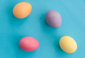 Colorful Easter Eggs on blue background. Orange, Purple, Yellow, Pink. Flat lay