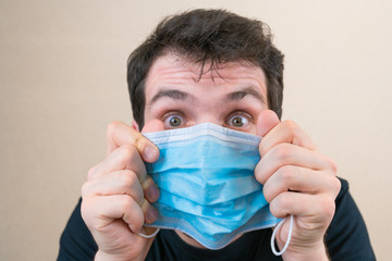 Young man in blue protective medical mask and happu with it. Self-isolation and quarantine. Stay home
