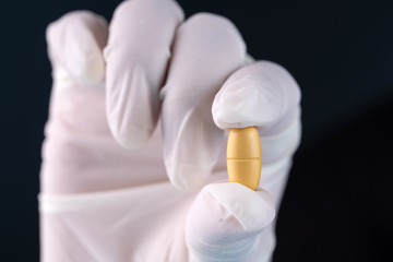 gloved hand holding a pill, cure to the coronavirus pandemic,covid-19