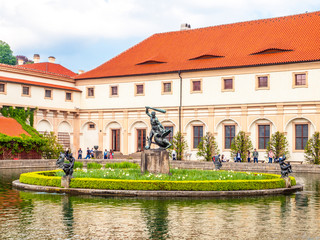 Fototapeta na wymiar Pool with small island and statue in baroque Wallenstein palace garden, Wallenstein Riding Hall on background, Prague, Czech Republic