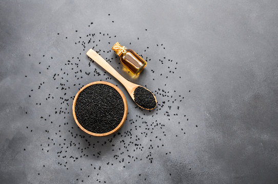 glass bottle of black cumin seeds essential oil , Nigella Sativa in spoon on rustic table. Organic herbal medicine for many diseases, black cumin