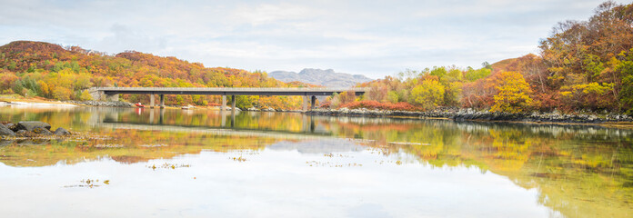 Fototapeta na wymiar Tranquil Autumn scene Scotland. Colourful trees and bridge reflected in calm water. Peacefulness.