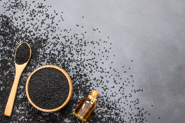 glass bottle of black cumin seeds essential oil , Nigella Sativa in spoon on rustic table. Organic...