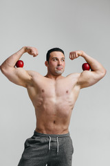 Sporty sexy guy posing on a white background with bright fruits. Diet. Healthy diet