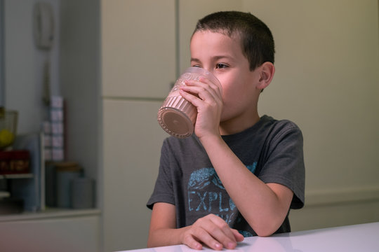 Un ni&ntilde;o toma chocolatada en la cocina frente a una ventana 