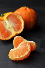 Orange tangerine citrus fruits on black background. Tangerine parts.