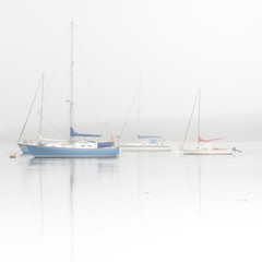 Sailing boats on misty lake