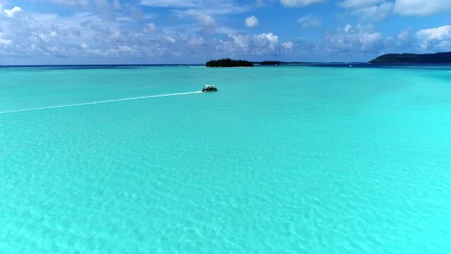 Amazing drone flying over the stunning turquoise blue water tropical island landscape of Bora Bora, French Polynesia. Boat travels through the shot.