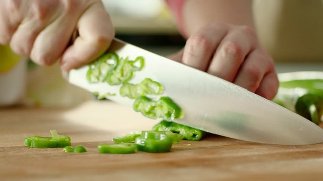 hands chopping green fresh pepper on a cutting board then throws peppers with a knife. Fast.